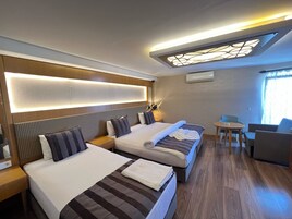 Una habitación de hotel con dos camas, una mesita y una silla.