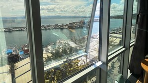 A high-rise hotel room with a large window overlooking a marina with boats and a distant shoreline. - The Port Rooms (Sinop)