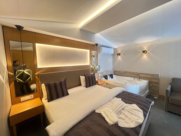 A modern hotel room with a large bed, a separate bathroom with a bathtub, and a seating area.