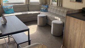 Un espace de vie chaleureux comprenant un canapé, des poufs, une petite table et un comptoir de cuisine.