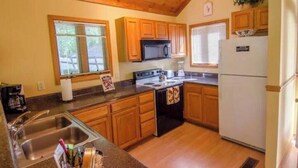 Una cocina con armarios de madera, estufa, microondas y refrigerador.