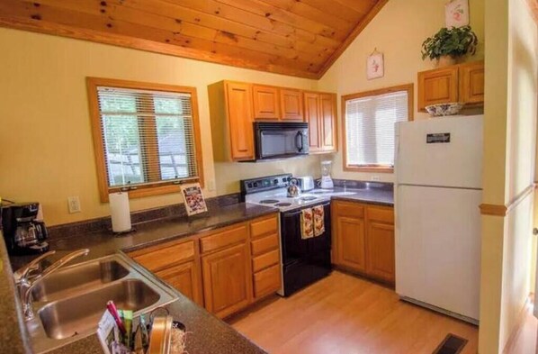 Una cocina con armarios de madera, estufa, microondas y refrigerador.