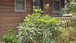 A wooden cabin with a front door, two windows, and a small porch with steps.