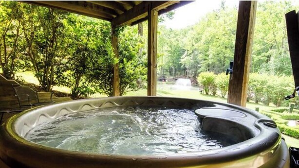 A hot tub with a view of a lush garden and a wooden pergola.