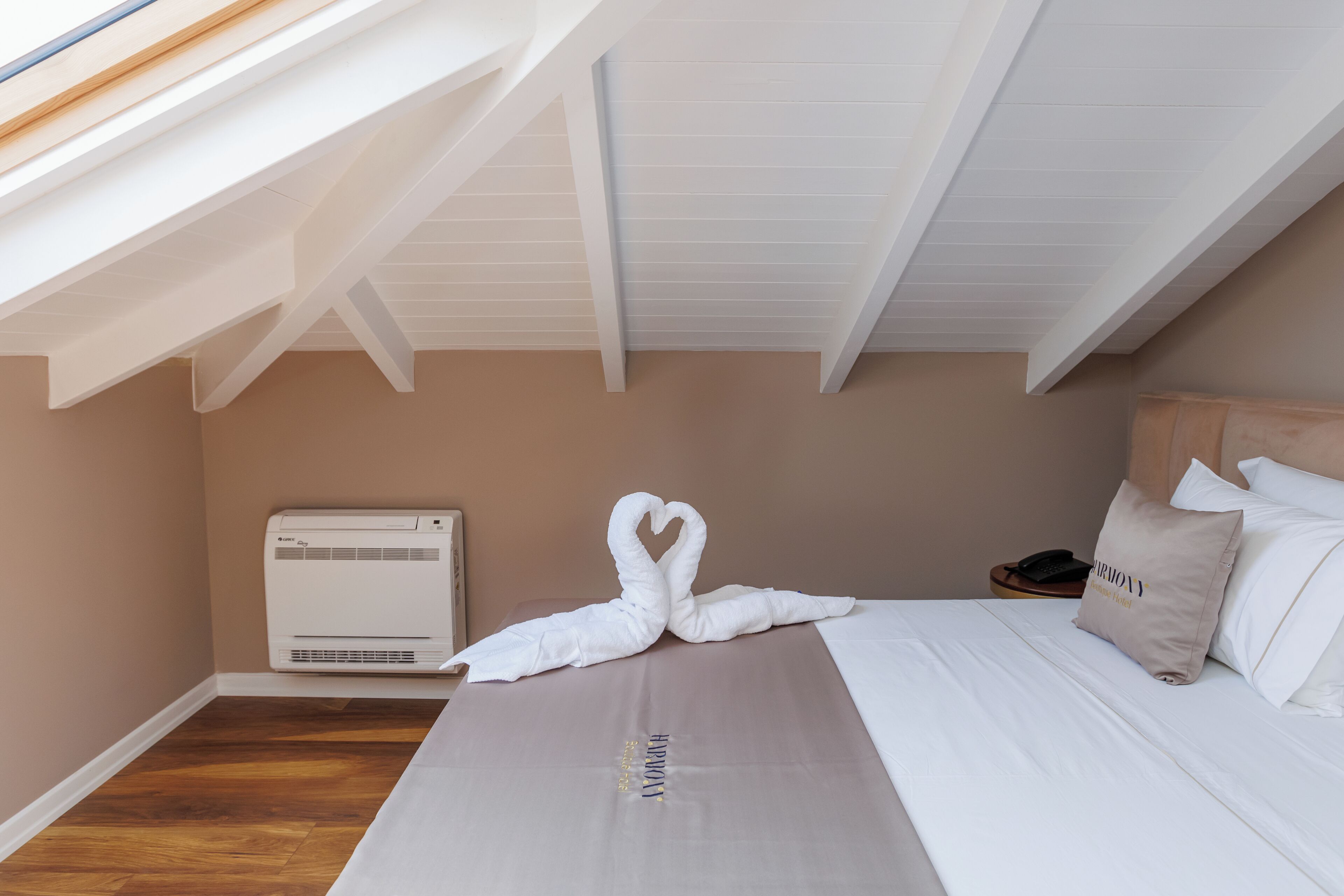A hotel room with a bed, a wall-mounted air conditioner, and a skylight.