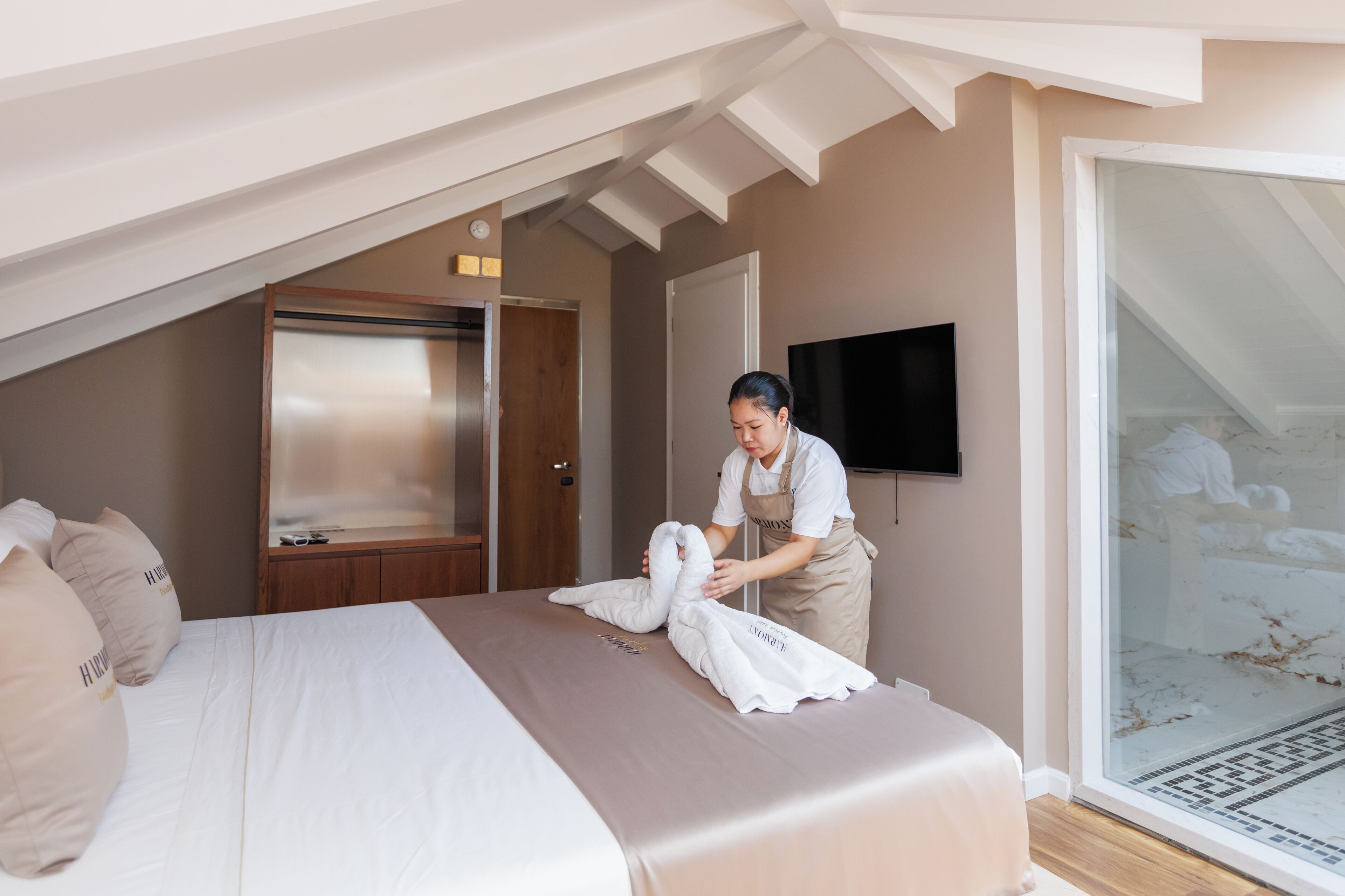 Habitación de hotel con cama, televisión y puerta corredera que da a un balcón.