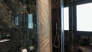 Ein modernes Badezimmer mit einer Duschkabine, Marmorwänden und einer Toilette.