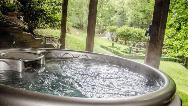 Een hottub met uitzicht op een tuin en een houten trap.