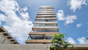 Un moderno edificio de gran altura con varios balcones y un cielo despejado.