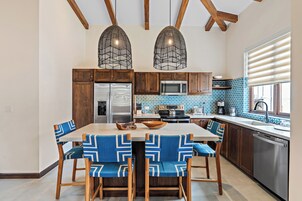 Una cocina moderna con armarios de madera, un refrigerador de acero inoxidable, un microondas y un respingo de azulejos azules.