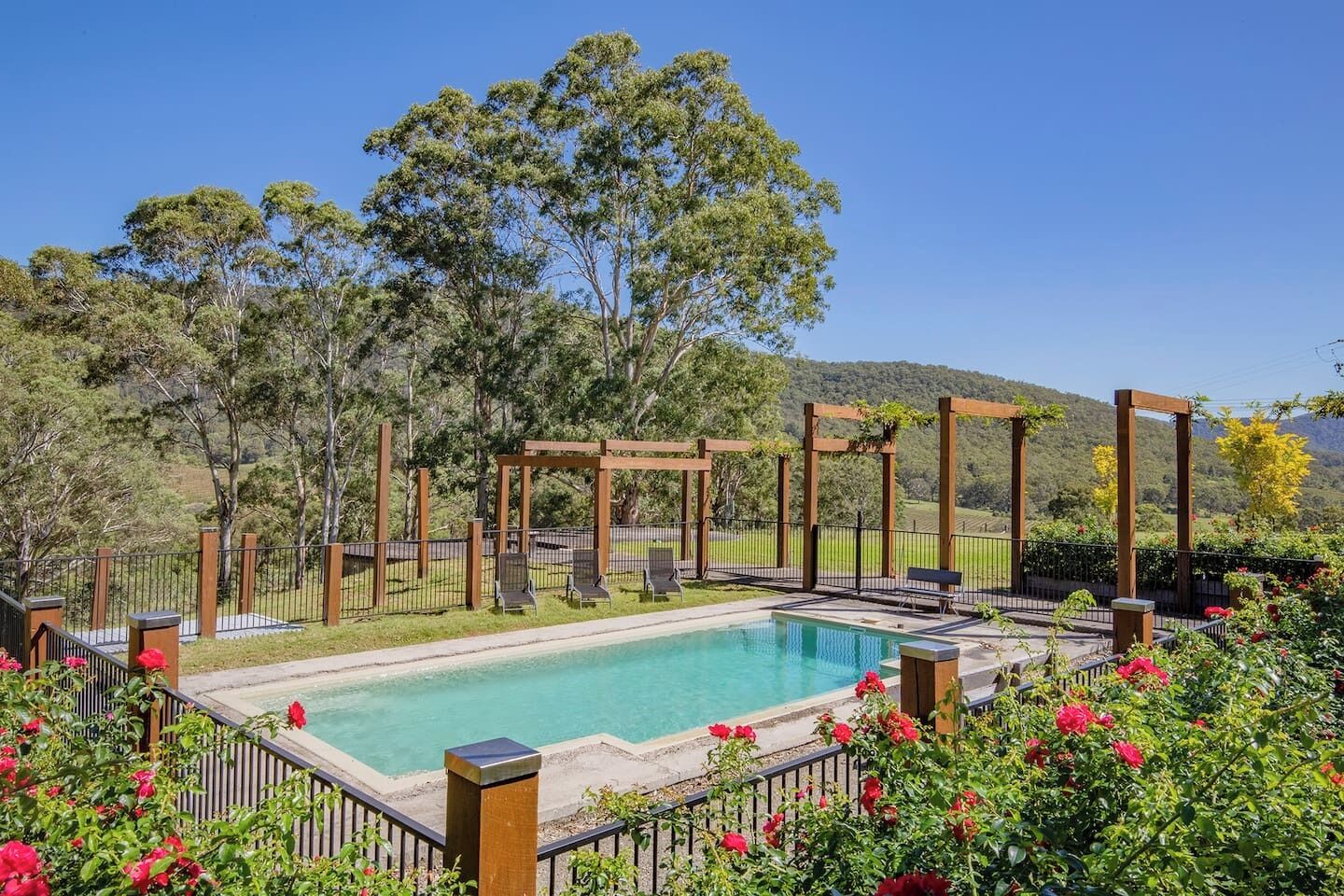 Swim among the roses—this sparkling pool is bordered by fragrant blooms and lush hedges, creating a private oasis under the Hunter Valley sun.