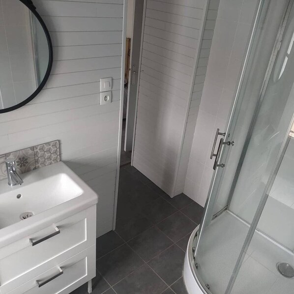 A bathroom with a white sink, mirror, and a glass shower enclosure.