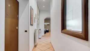 Un couloir avec un radiateur, des tableaux encadrés accrochés au mur et une fenêtre avec des stores.