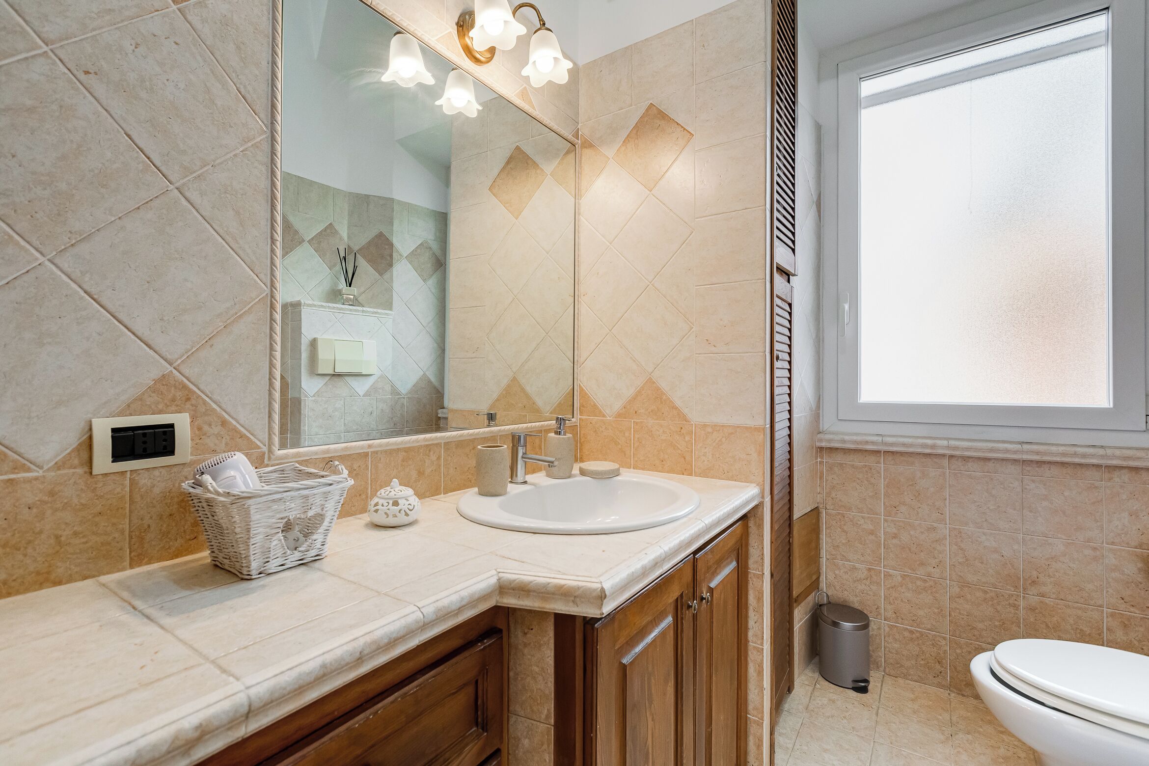A bathroom with a sink, mirror, and window.