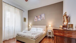 Une chambre à coucher comprenant un lit, des tables de chevet, une commode et des œuvres d’art murales.