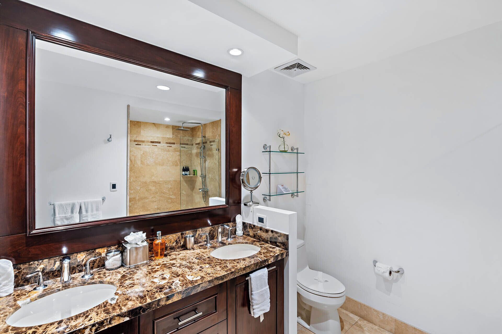 A modern bathroom with two sinks, a large mirror, and a glass shower enclosure.