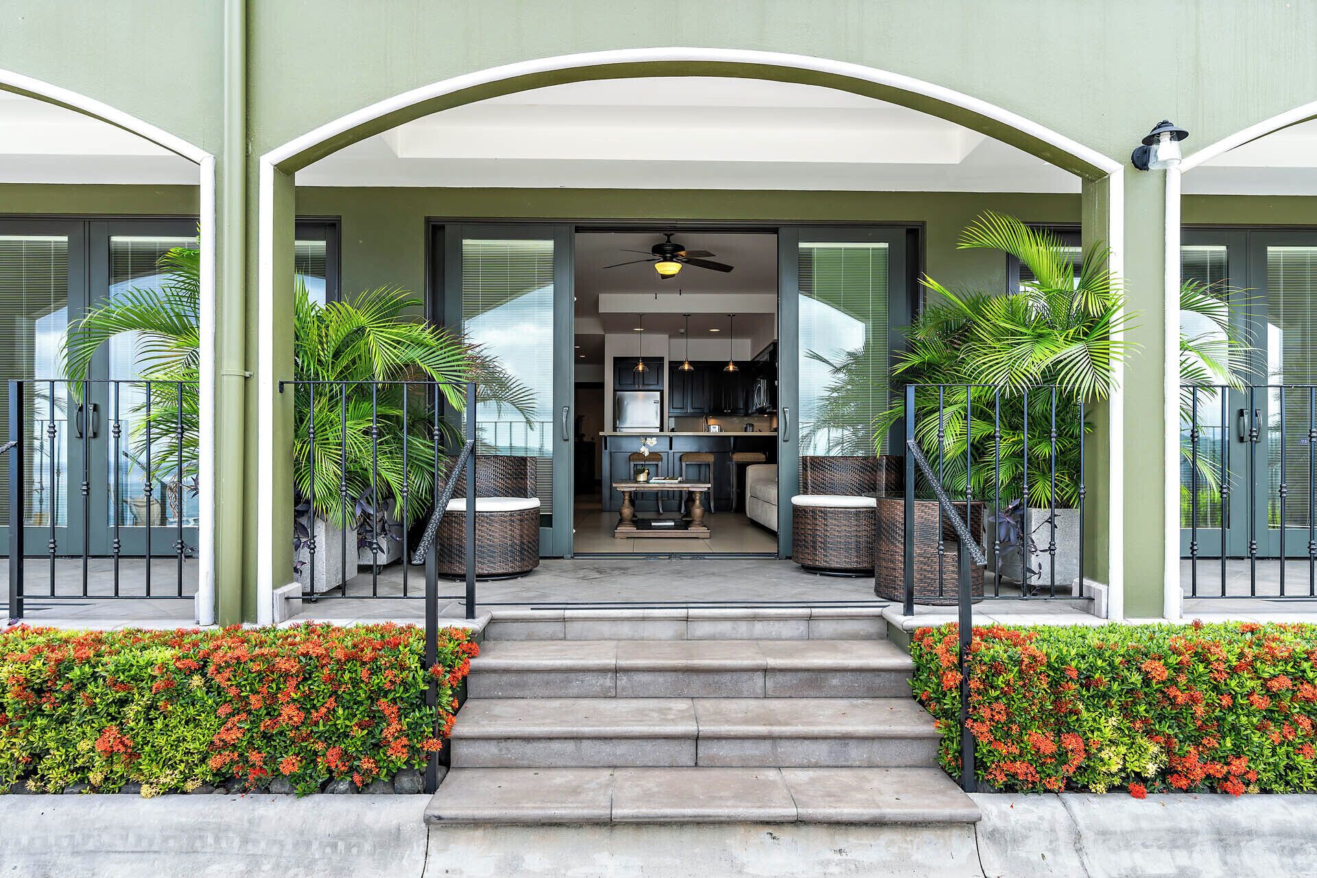 A modern building entrance with a covered staircase, potted plants, and a view into the interior.