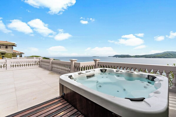 A hot tub on a balcony with a view of the sea and hills. - Luxury Condo with Panoramic Ocean Views, Sparkling Infinity Pool, and Modern Open-Concept Design (Cabo Velas)