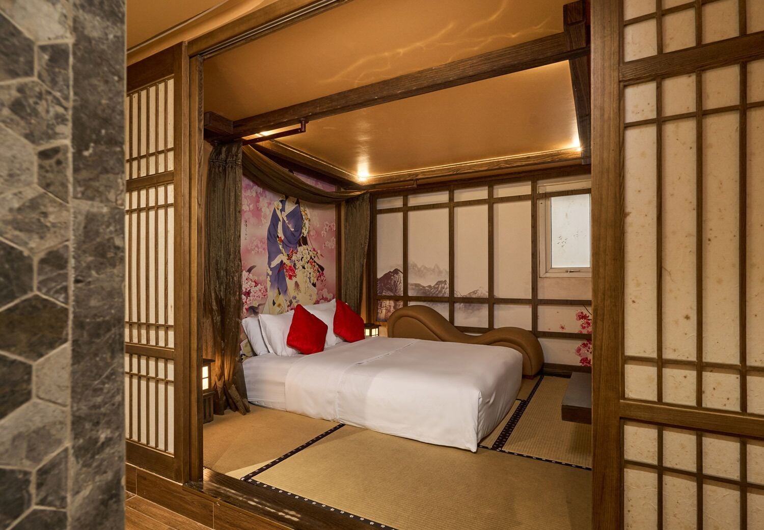 Una habitación tradicional japonesa con suelo de tatami, una cama baja con almohadillas rojas y una puerta corredera de shoji.