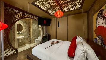 A bedroom with a bed, a hanging lantern, a painting, and a TV screen displaying the Netflix logo.