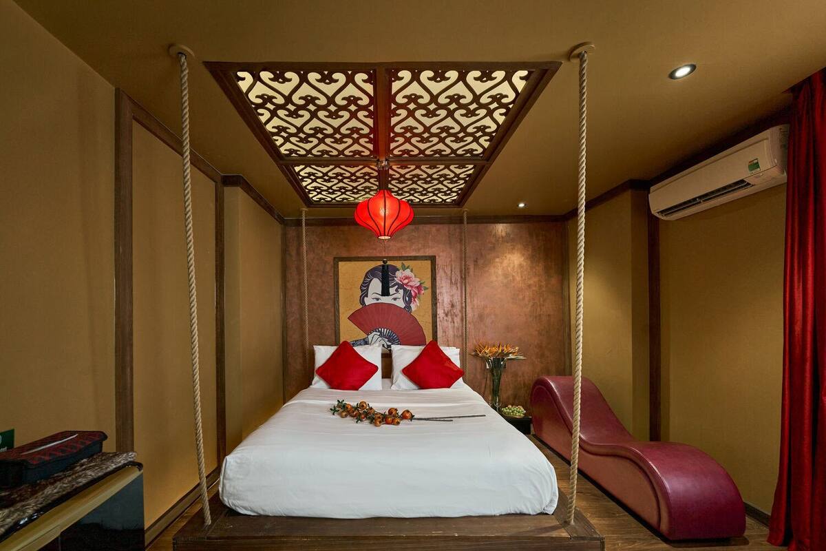 A room with a bed suspended from the ceiling, a massage chair, and a wall-mounted air conditioner.