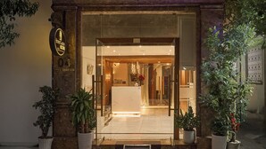 A hotel entrance with a double door, potted plants, and a sign indicating the name and address. - Secret Garden Hotel Ben Thanh (Ho Chi Minh City)