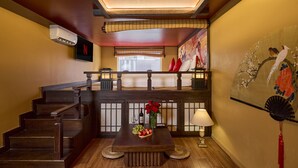 A wooden staircase leading to a balcony with a view of the outdoors. A wooden table with a vase of flowers and a wine bottle is placed in the foreground. - Secret Garden Hotel Ben Thanh (Ho Chi Minh City)