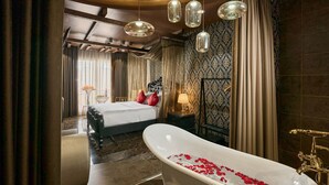 A luxurious bedroom with a large bed, a bathtub with rose petals, and a chandelier. - Secret Garden Hotel Ben Thanh (Ho Chi Minh City)