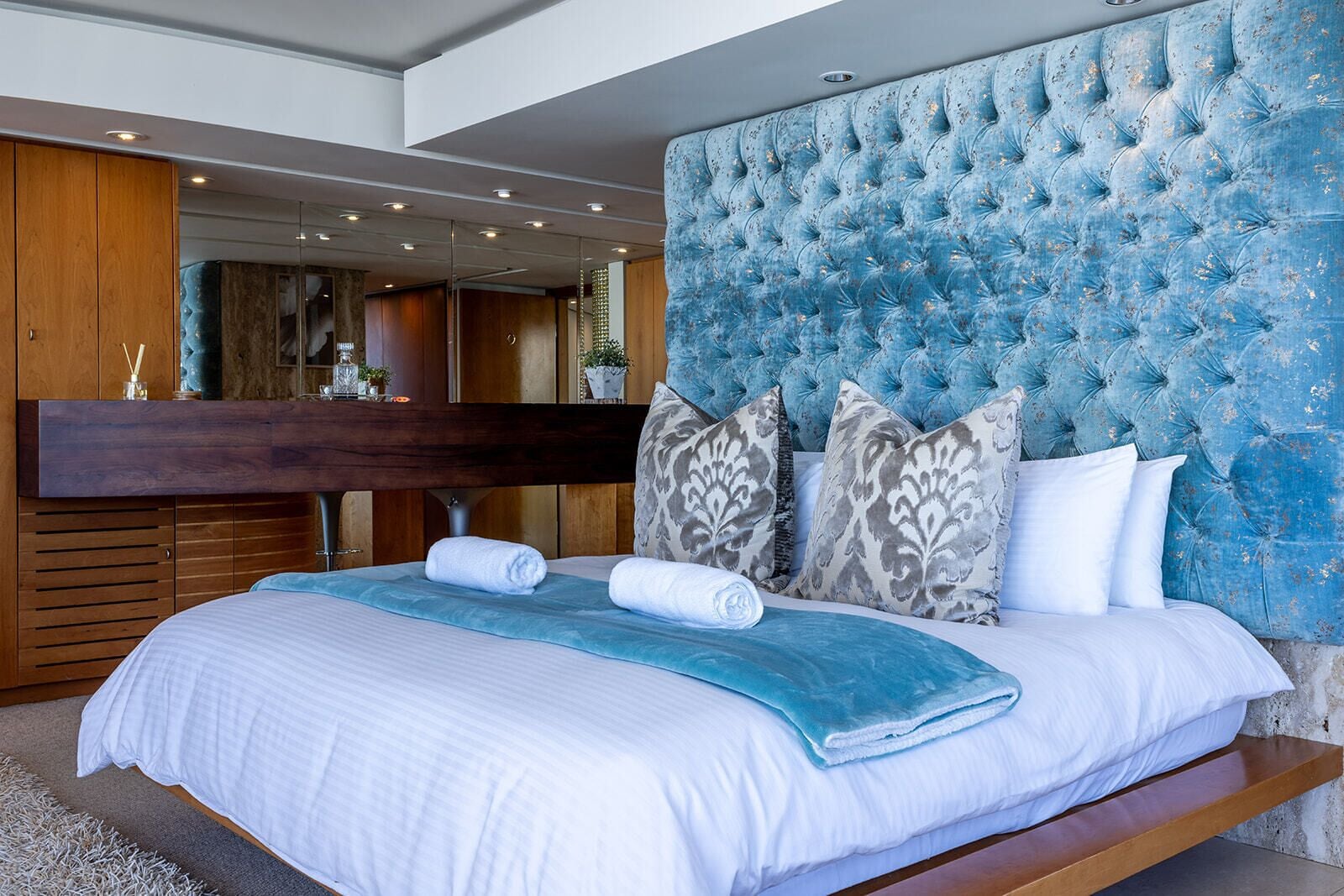 Un dormitorio con una cama grande, cabecera de madera y tocador empotrado con espejo.
