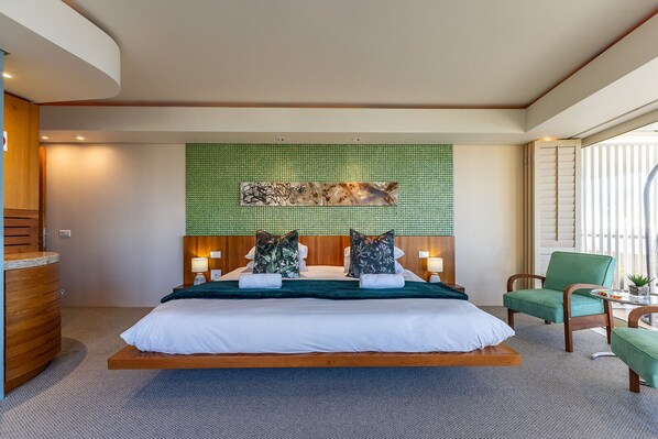 A spacious bedroom with a large bed, a green textured wall, and a wooden headboard. - The Marvel Beach House (Cape Town)