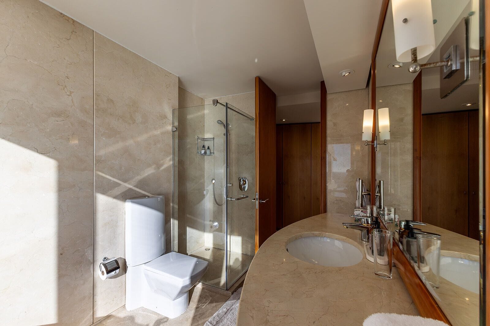 Un bagno moderno con doccia vetro, lavabo doppio e un grande specchio.
