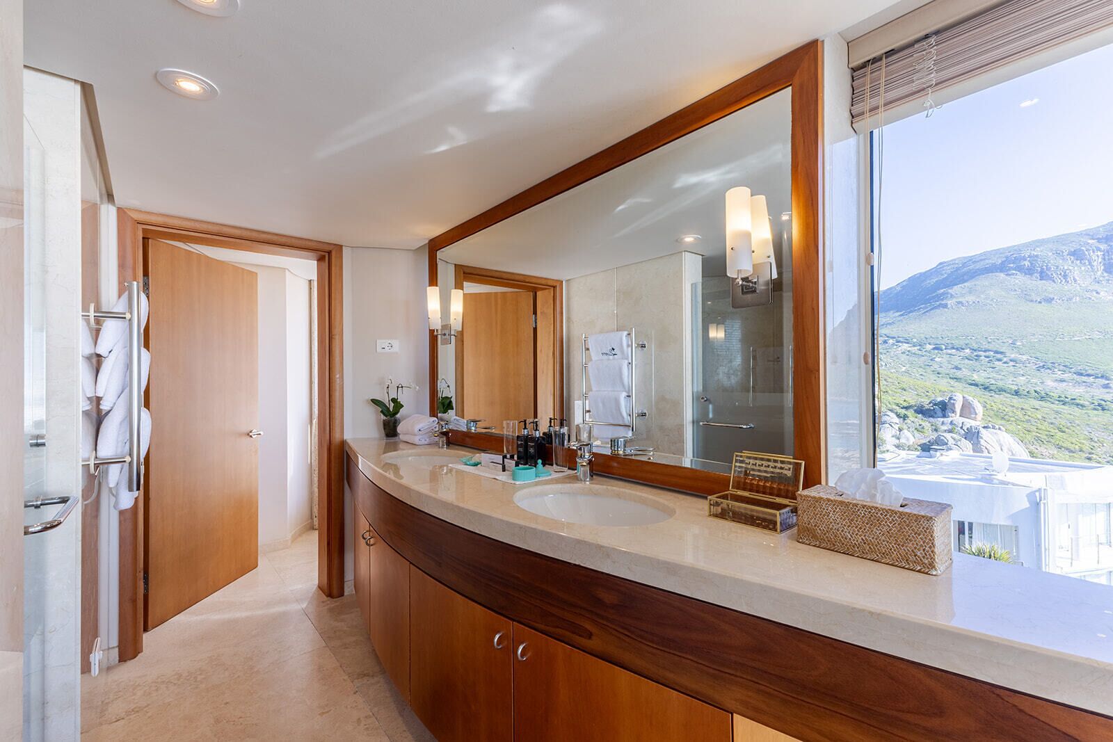 A modern bathroom with two sinks, a large mirror, and a view of a mountainous landscape.