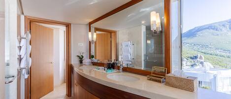 A modern bathroom with two sinks, a large mirror, and a view of a mountainous landscape.
