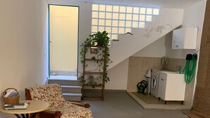 Ein kompakter Wohnraum mit einer Couch, einem kleinen Tisch, einer Treppe und einer Küchenzeile.
