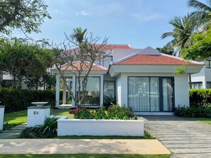 Stunning garden surrounds this well-maintained home with a red-tiled roof and large windows.