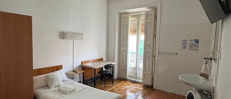 Une chambre d’hôtel comprenant un lit, un bureau, une chaise et une salle de bain avec un lavabo et un miroir.