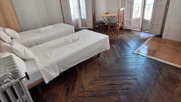 Een kamer met twee bedden, een tafel met stoelen en een radiator.