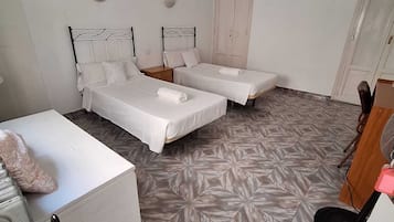 Una habitación con dos camas individuales, una mesita, una silla y un radiador.
