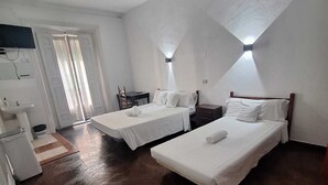 Een kamer met twee bedden, een bureau, een stoel, een wastafel en een televisie.