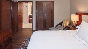 A hotel room with a large bed, a wooden wardrobe, a chair, a nightstand with a lamp, and a bathroom visible through an open door. - HGVC Hokulani Waikiki Luxury, 1 BR Suites, Rooftop Pool/Spa, Close to Ft Derussy (Honolulu)