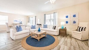 A spacious living room with a round coffee table, white sofas, and a ceiling fan. - Last Minute Disney Getaway! Private Pool, Hot Tub & Game Room. Book Now! #CG346 (Orlando)
