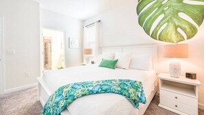 A bedroom with a bed, a nightstand, a lamp, and a large tropical leaf decoration. - Last Minute Disney Getaway! Private Pool, Hot Tub & Game Room. Book Now! #CG346 (Orlando)