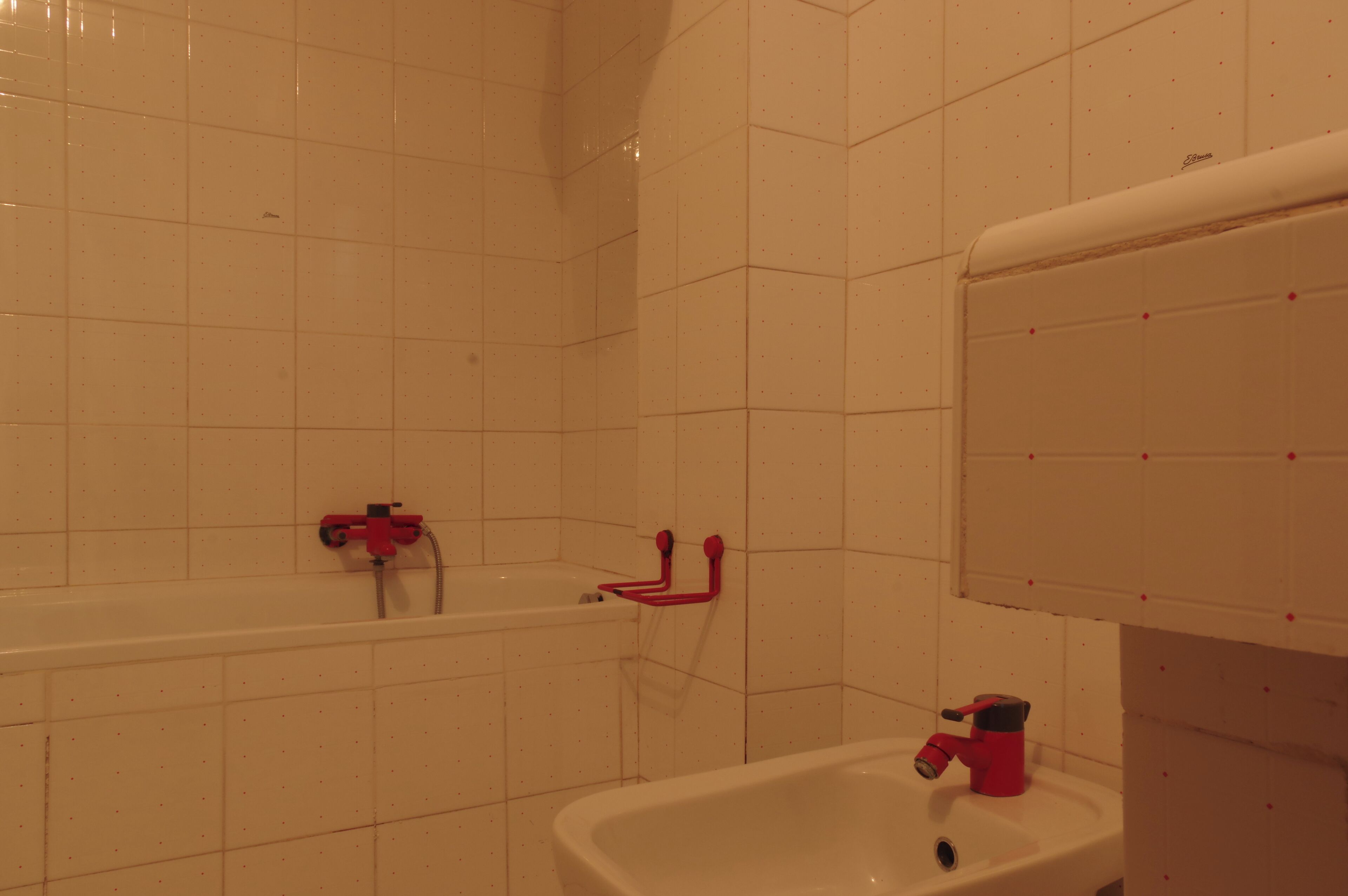 A bathroom with white tiled walls, a bathtub, a sink, and a toilet.