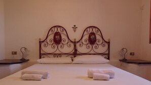 A neatly made bed with white linens and two rolled towels.