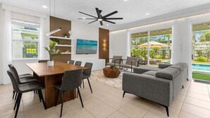 A modern living room with a dining area, large windows, and a pool view. - Last Minute Disney! Private Pool, Hot Tub, Game Room & Themed Bedrooms. Book Now! #20220 (Orlando)