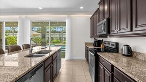 A modern kitchen with granite countertops, dark cabinetry, and a built-in microwave. - Last Minute Disney! Private Pool, Hot Tub, Game Room & Themed Bedrooms. Book Now! #20220 (Orlando)