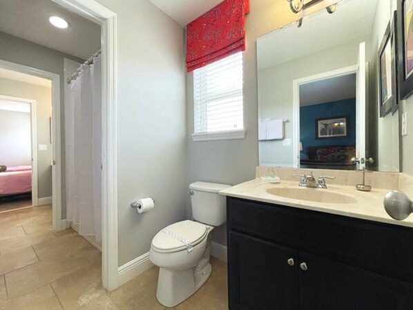 A bathroom with a toilet, sink, and mirror.