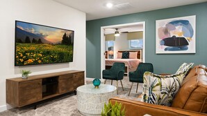 A living room with a large flat-screen TV, a round coffee table, a brown leather sofa, and two green armchairs. - Last Minute Disney! Private Pool, Hot Tub, Game Room & Themed Bedrooms. Book Now! #38250 (Orlando)