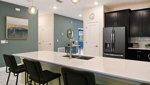 A modern kitchen with a large island, black cabinets, stainless steel appliances, and pendant lighting. - Last Minute Disney! Private Pool, Hot Tub, Game Room & Themed Bedrooms. Book Now! #38250 (Orlando)