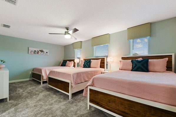 A bedroom with three beds, a ceiling fan, and a wall-mounted shelf with decorative items.